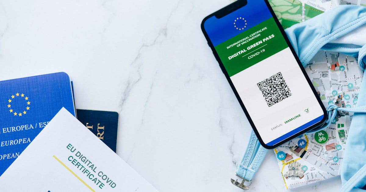 Smartphone displaying EU digital certificate alongside EU passport and QR code documents